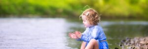 adorable girl playing at river shore